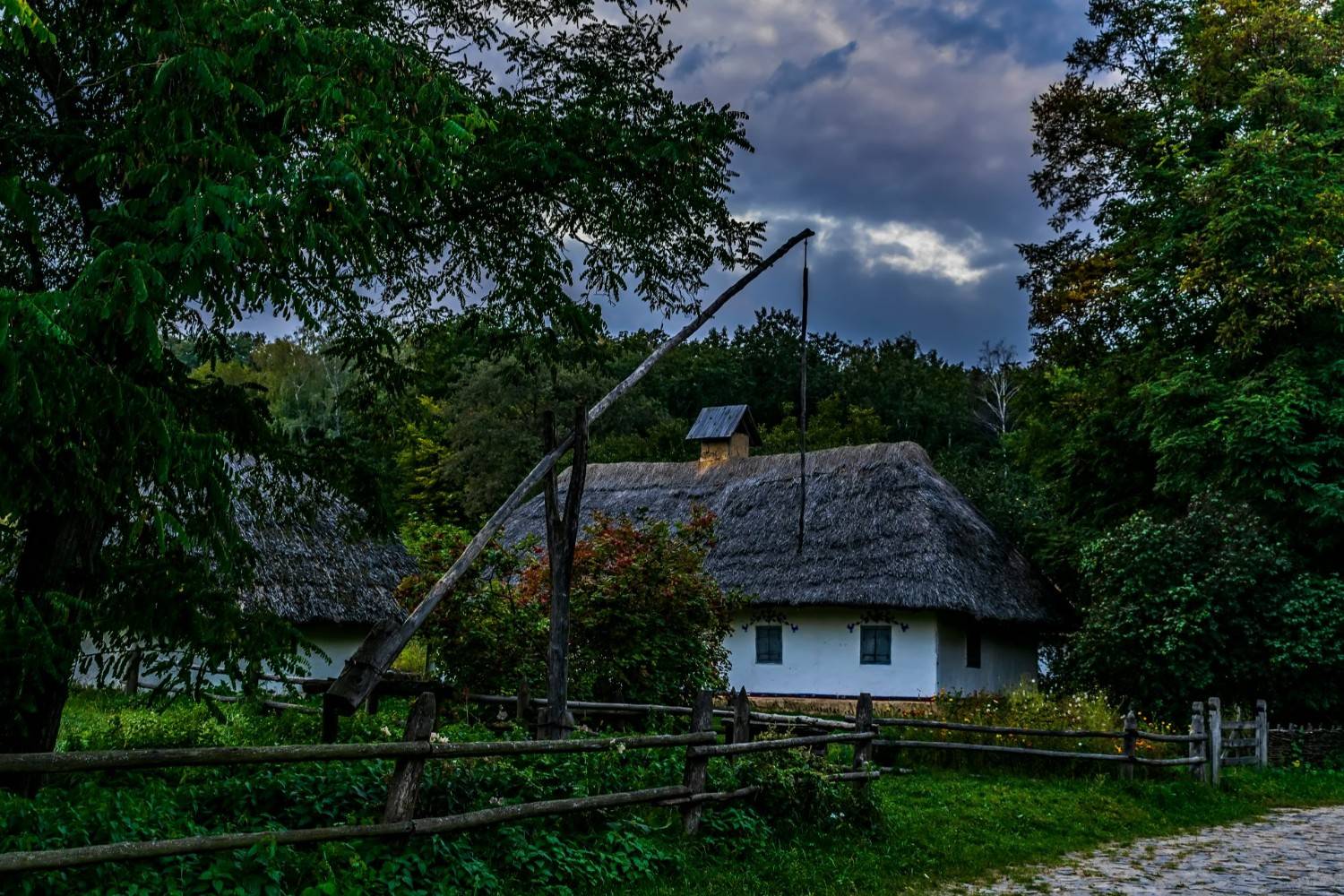 a white house with a thatched roof surrounded by trees