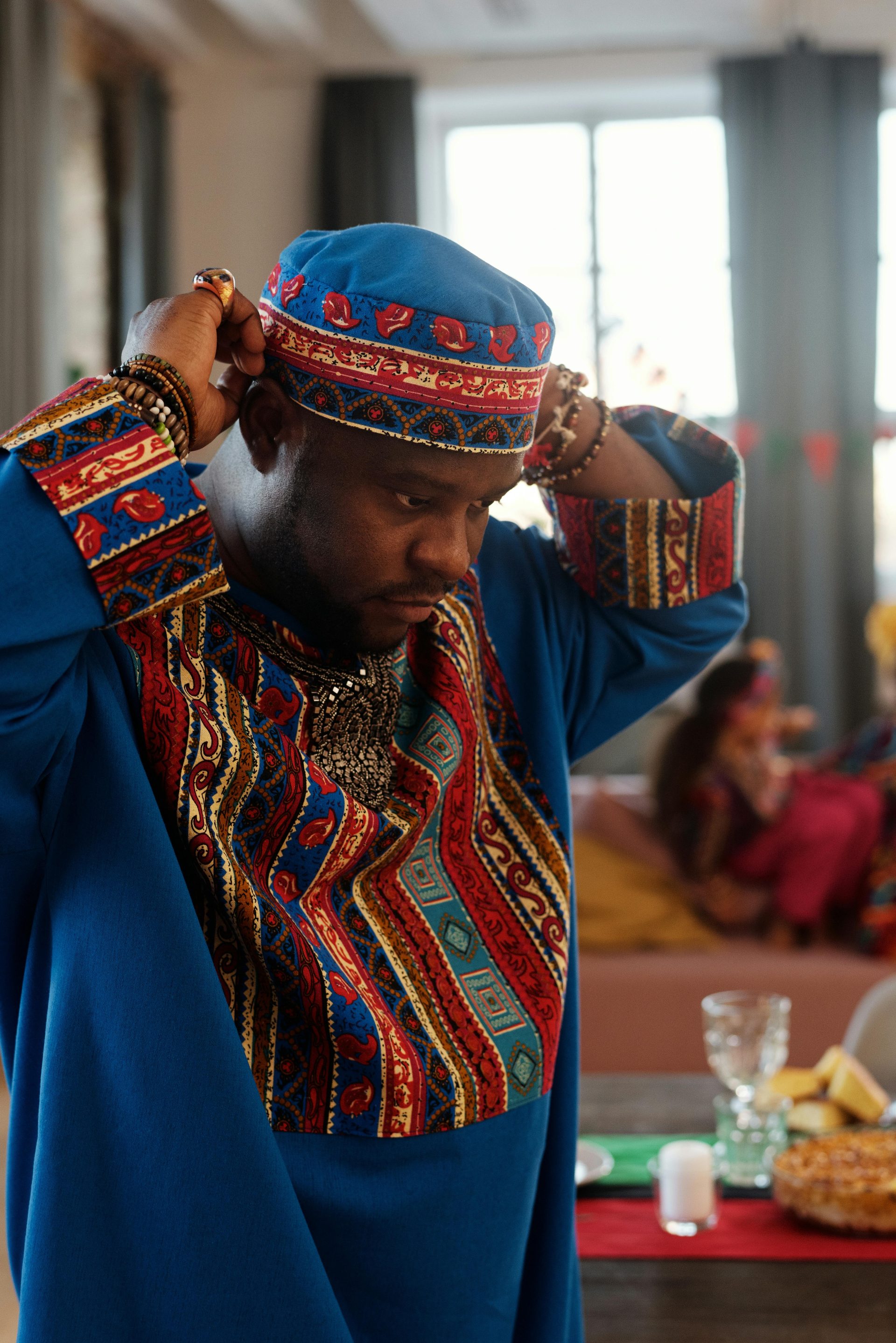African American man adjusting his dashiki at a cultural celebration indoors.