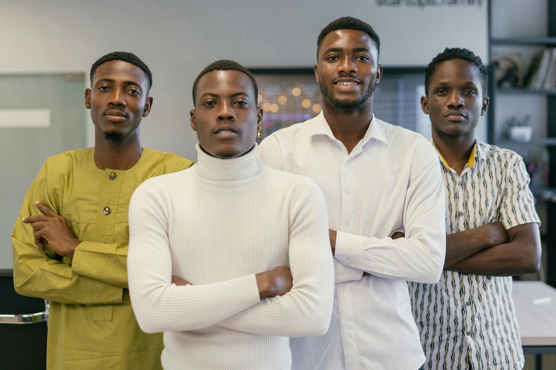 A group of four confident men standing in an office, expressing teamwork.